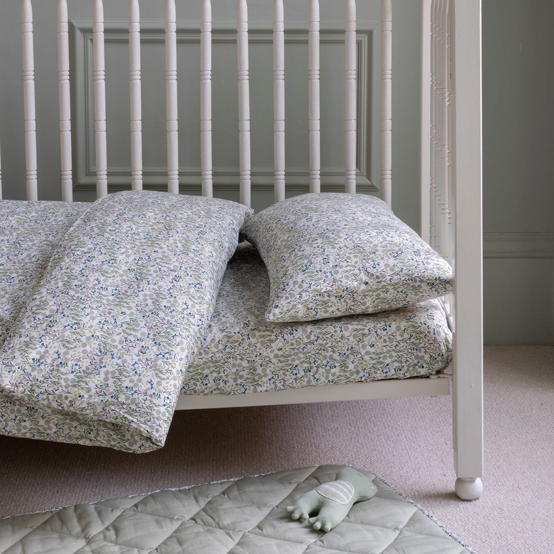 Children's bed with floral bedding and pillows in a room setting.