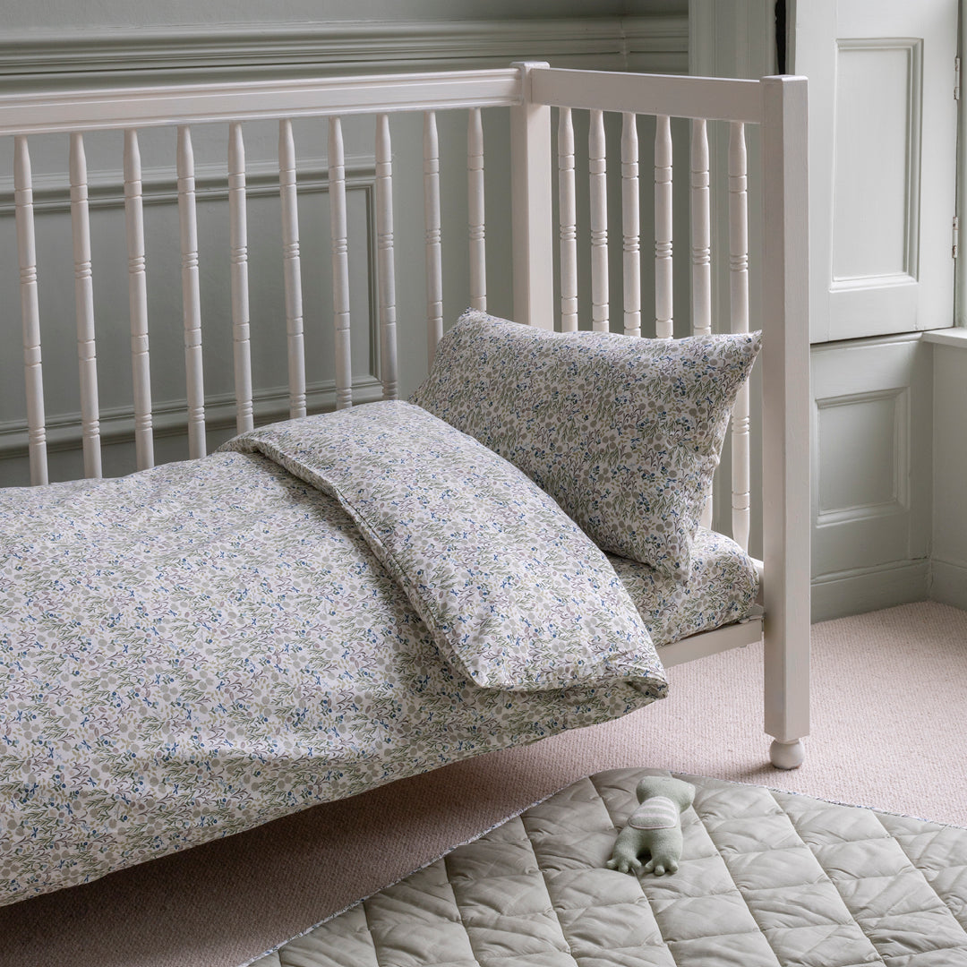White crib with floral bedding in a softly lit room