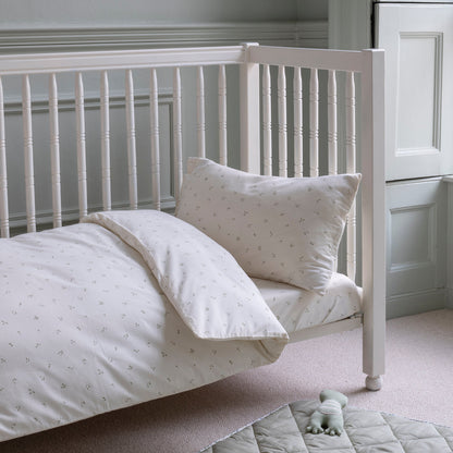 White crib with bedding and a pillow in a nursery setting