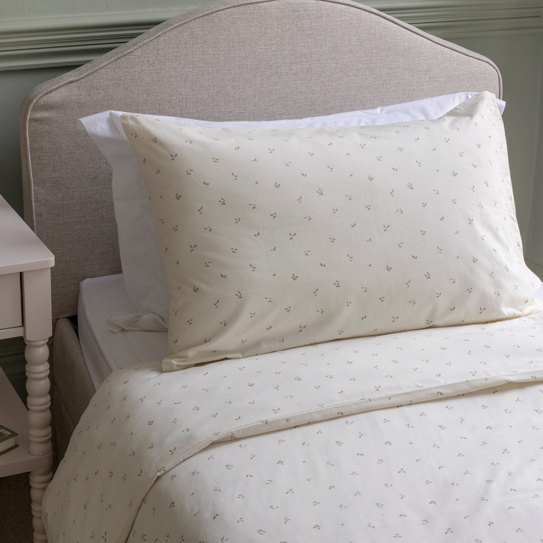 Neatly made bed with white bedding and pillows against a neutral headboard.