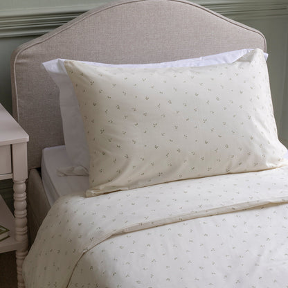 Neatly made bed with white bedding and pillows against a neutral headboard.