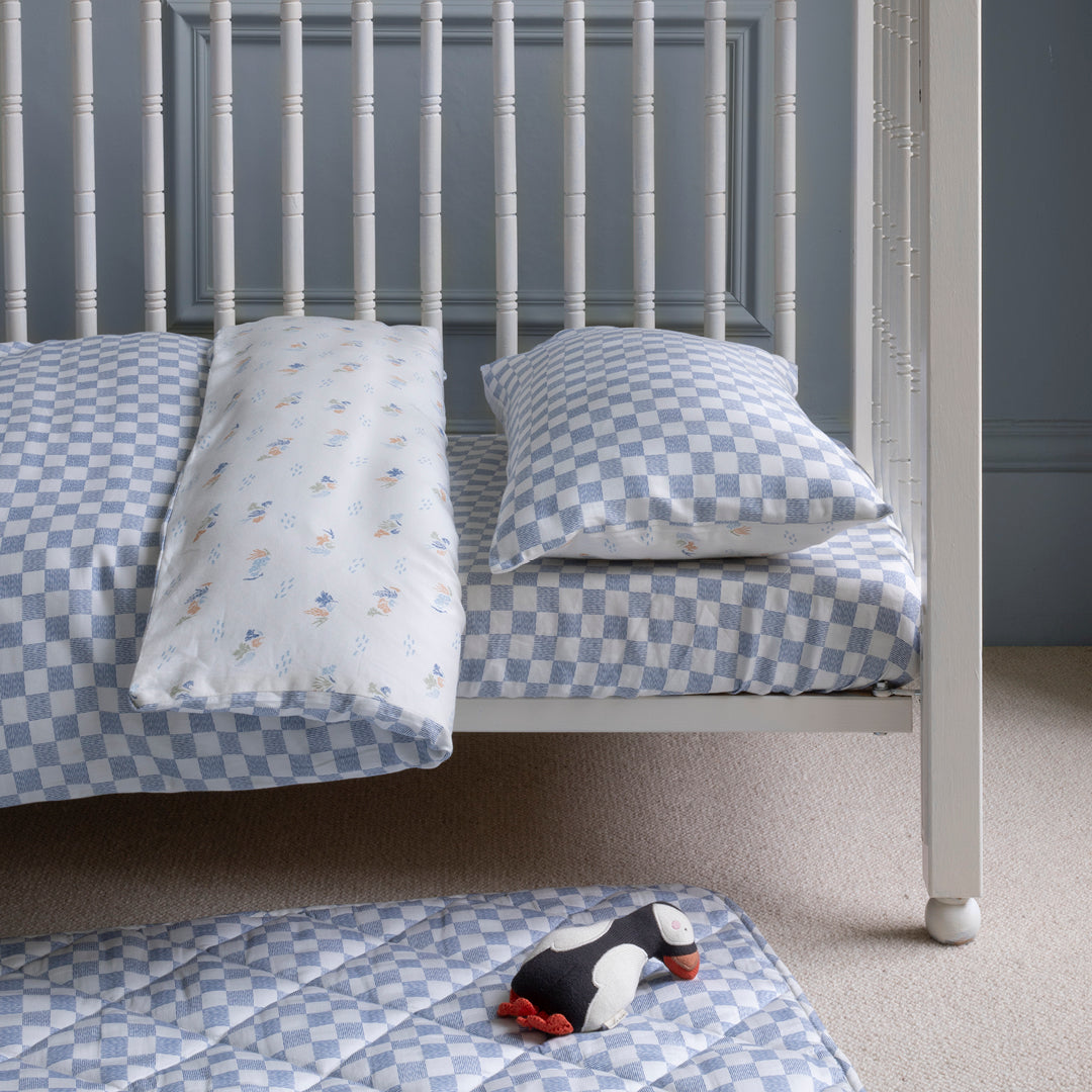 Children's checkered bedding set on a bed with a gray wall background