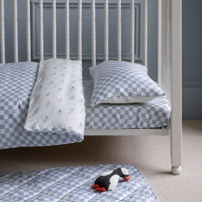 Children's checkered bedding set on a bed with a gray wall background