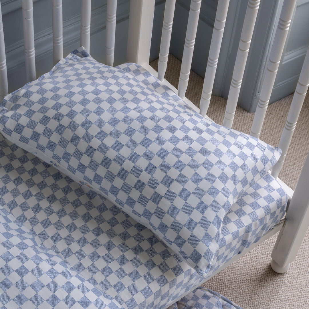 Checkered crib sheet on a white crib with blue checkered pattern