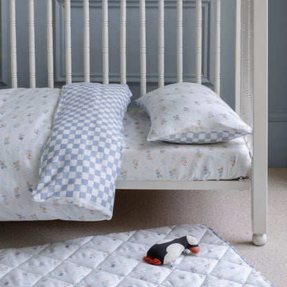 Children's bed with checkered bedding and a toy on a matching mattress.