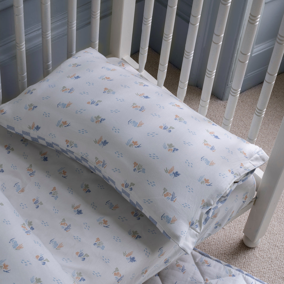 Crib with floral-patterned bedding and pillow