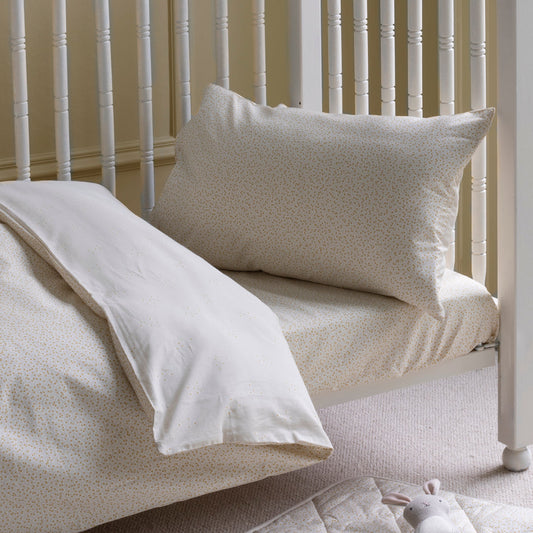 Beige pillow and duvet on a white spindle bed with a neutral background