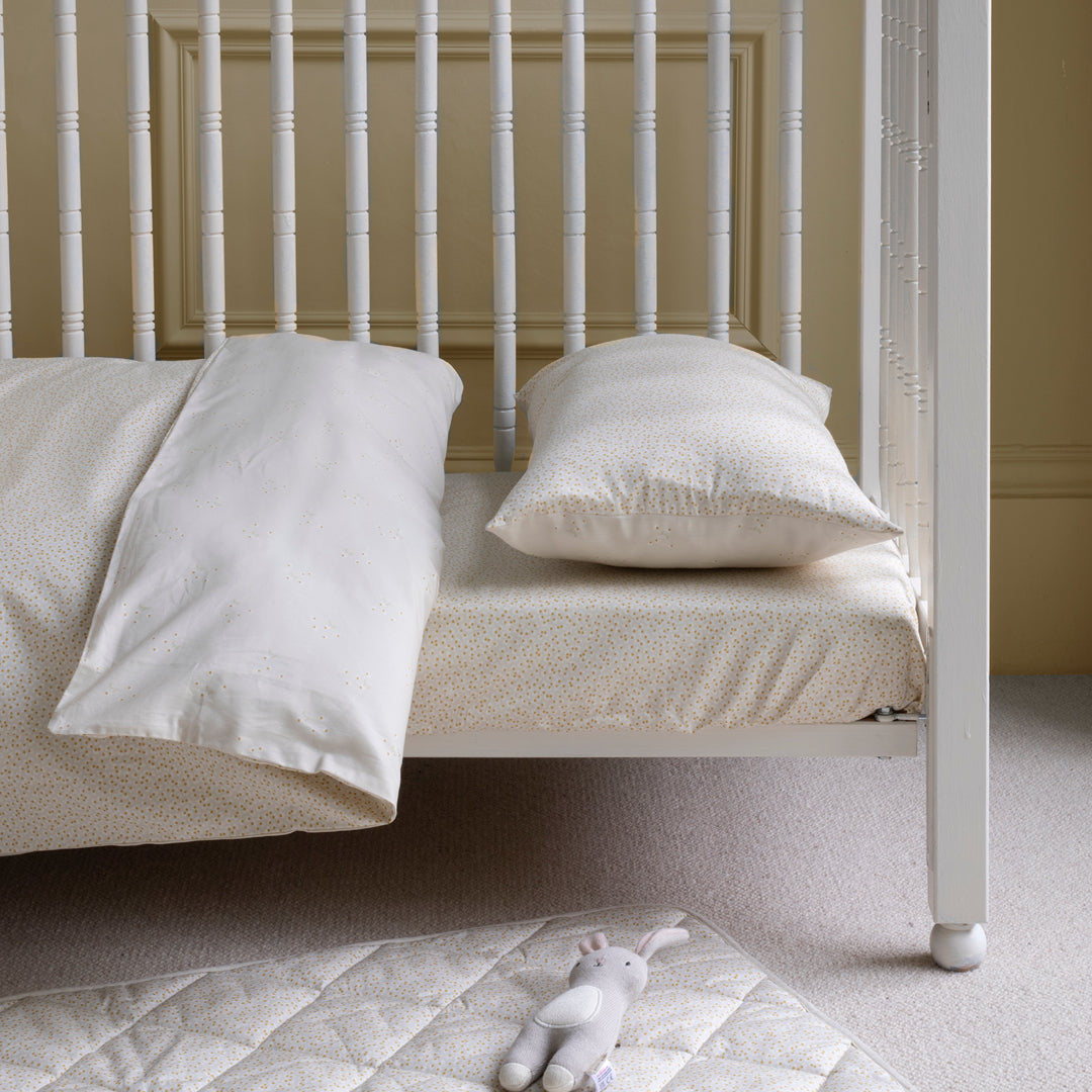 White crib with pillows and a stuffed animal on a carpeted floor.