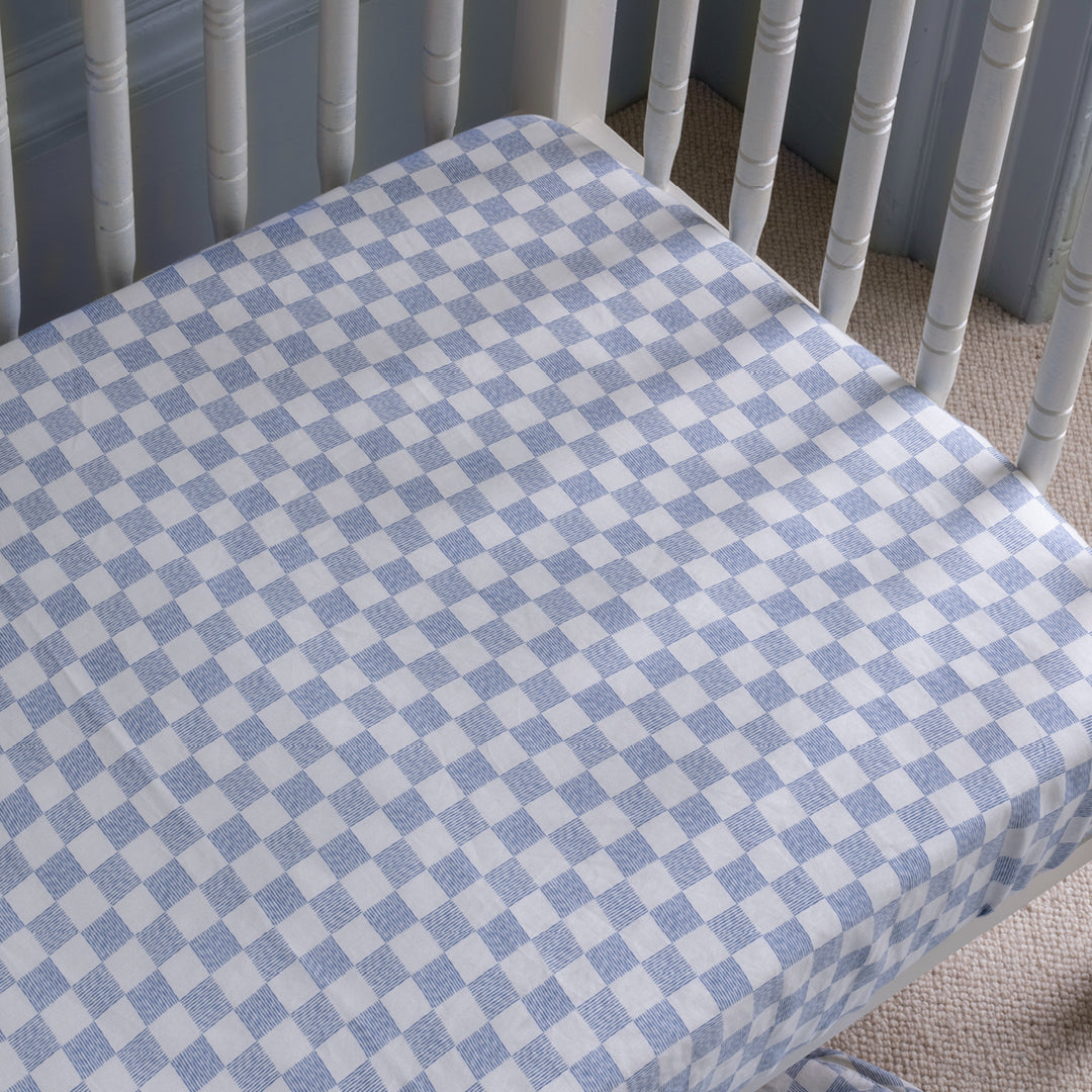 Crib with a blue and white checkered fitted sheet
