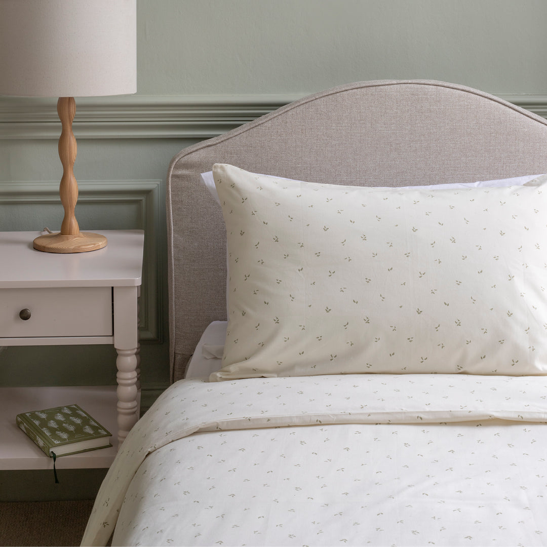Neatly made bed with patterned bedding in a bedroom setting.