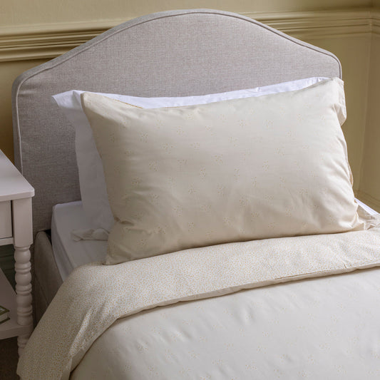 Neatly made bed with beige pillows and bedding in a bedroom setting.