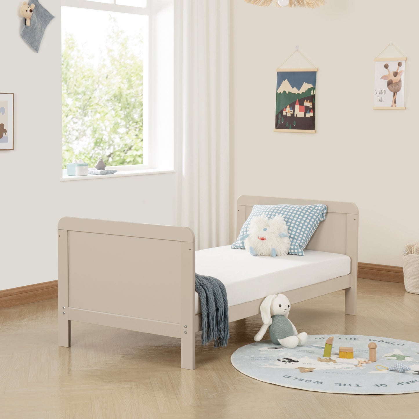 Children's bedroom with a beige bed, toys, and a window.