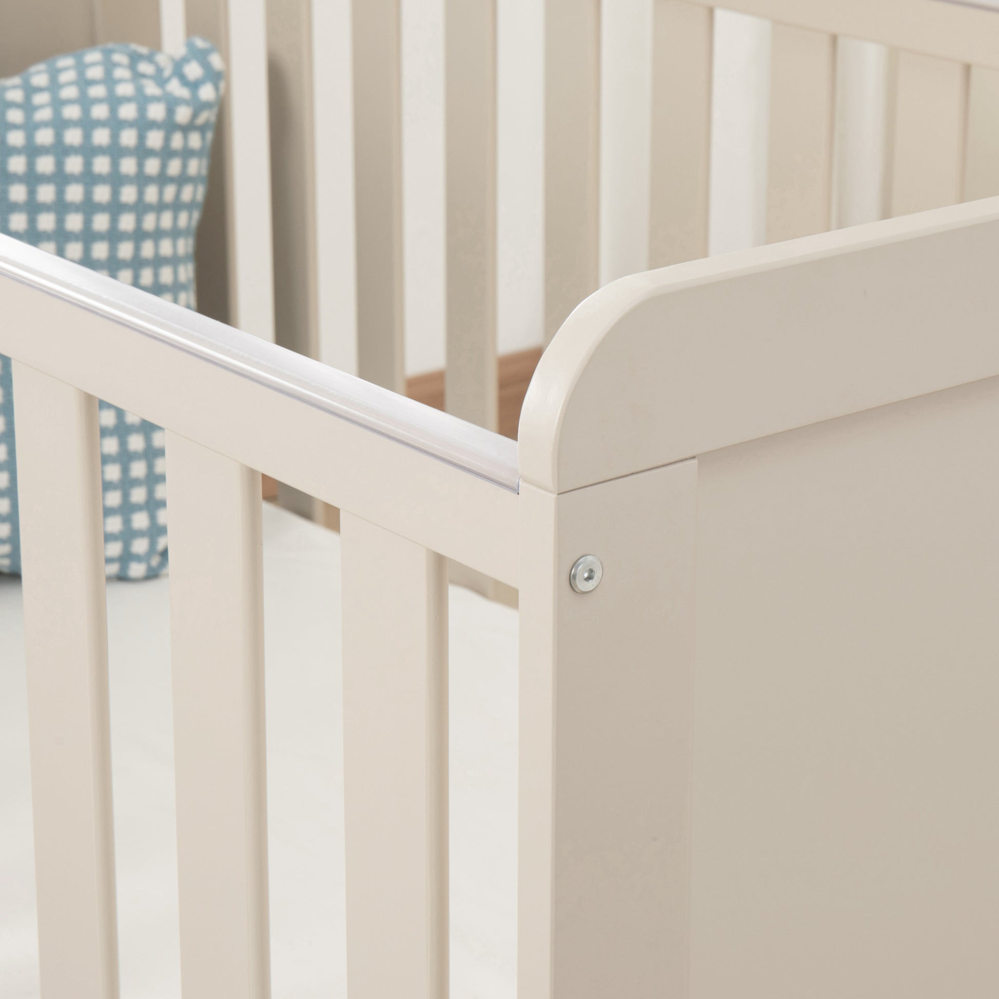 Cashmere Cot with a blue and white checkered pillow in the corner