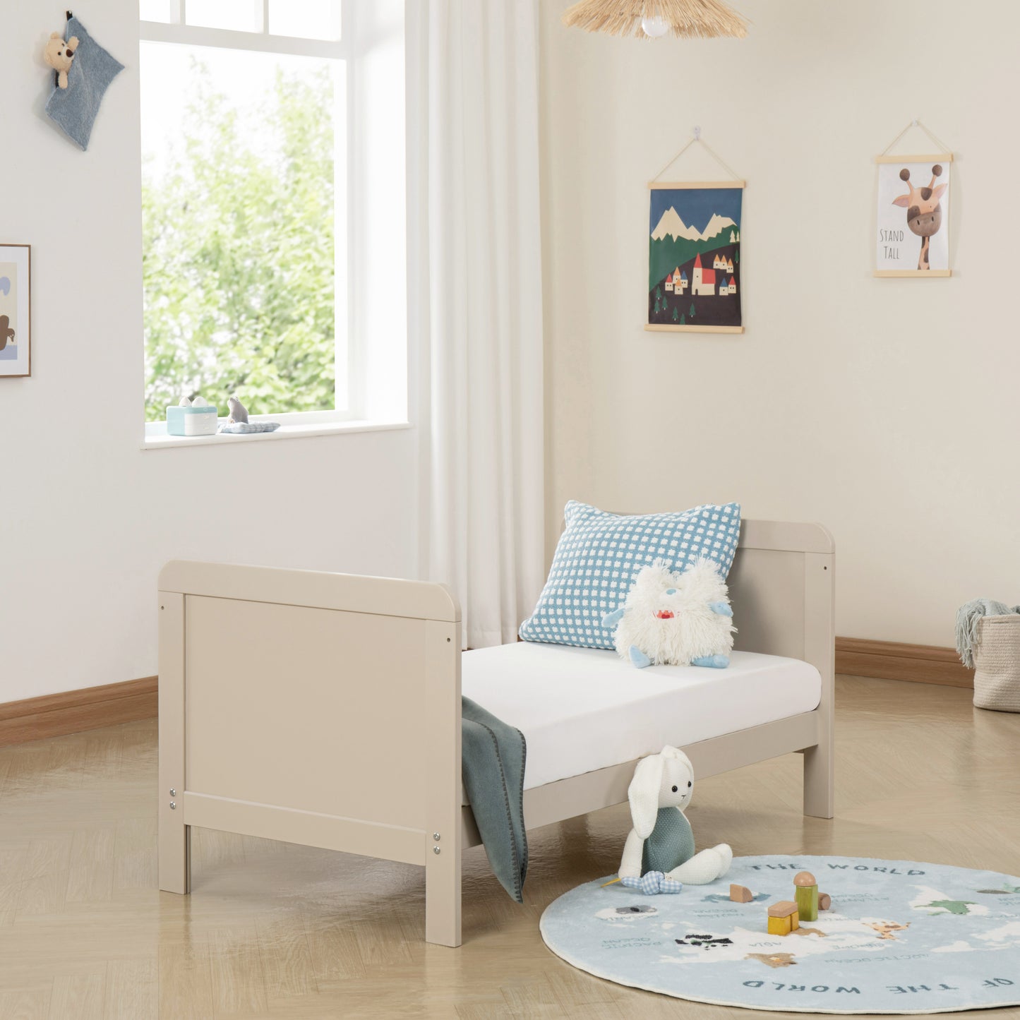 Children's room with a wooden cashmere bed, plush toys, and a round rug.