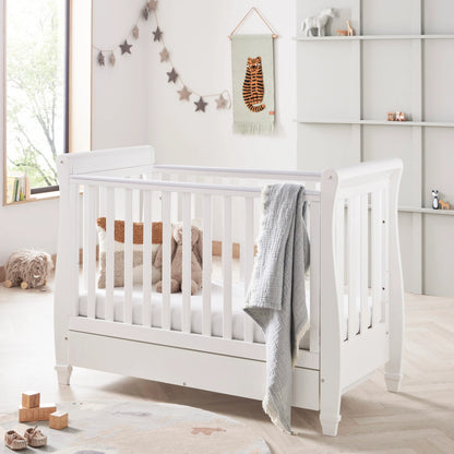 White crib in a nursery with decorative elements and toys.