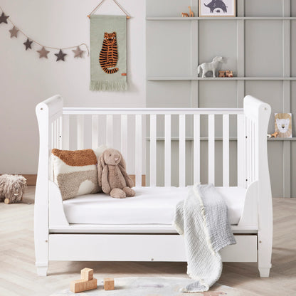 White crib in a nursery with toys and decorations