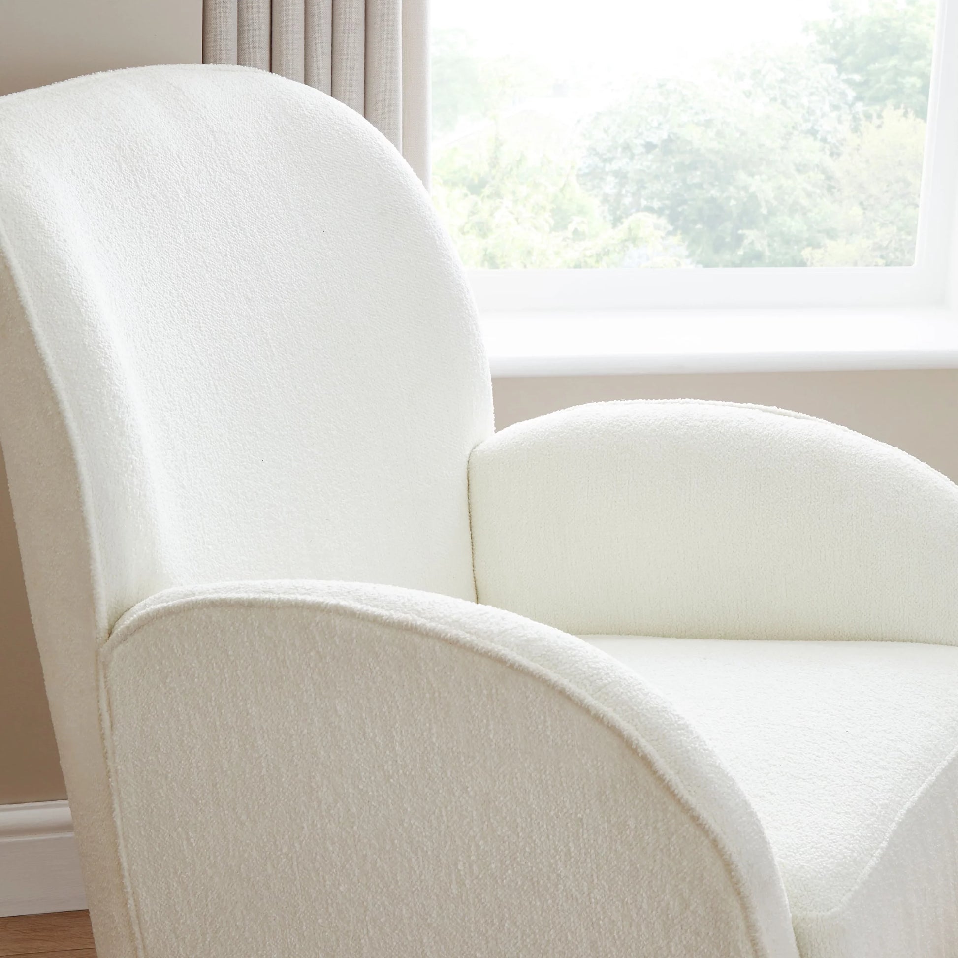 White armchair in a room with a window in the background