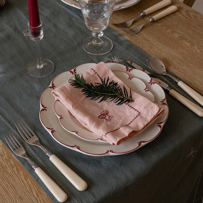 Set table with plates, napkin, and cutlery on a wooden surface.