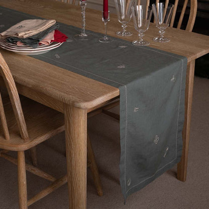 Dining table with a gray table runner, plates, and glasses.