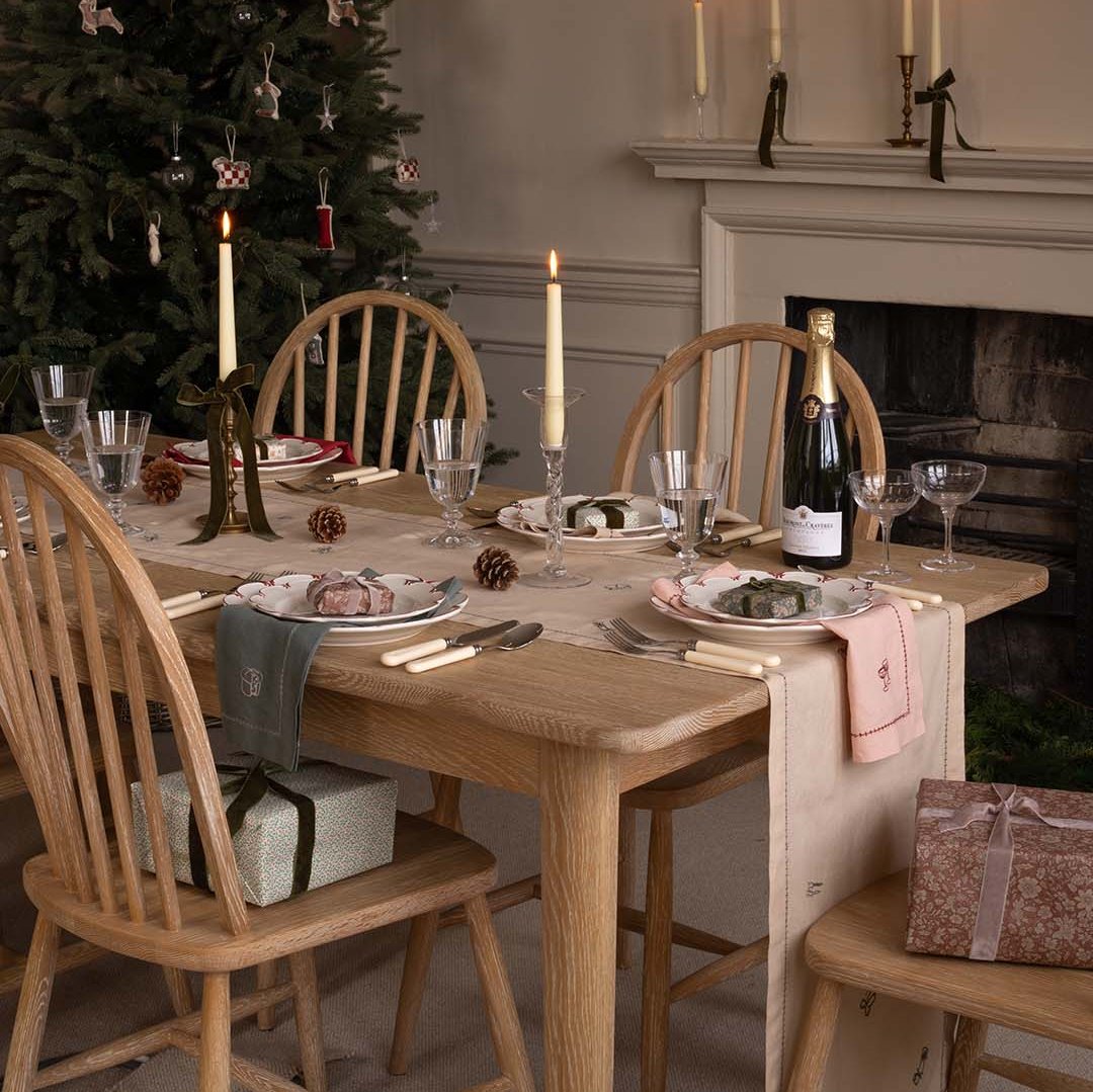 Dining table set for a meal with candles, wine glasses, and decorative items in a cozy room.