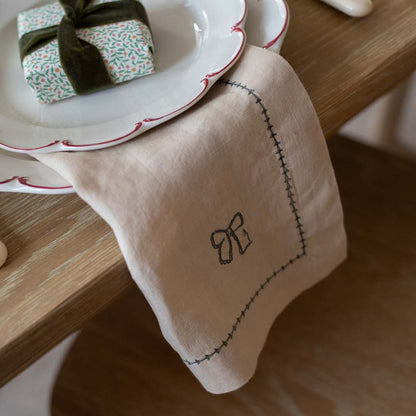 Beige napkin with embroidered bow design on a wooden table