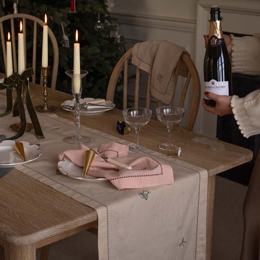 Dining table set for a meal with a bottle of wine, candles, and decorative elements.