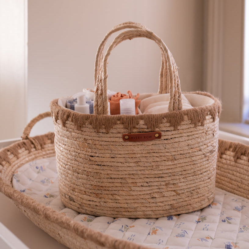 Woven basket with baby items on a crib with floral bedding