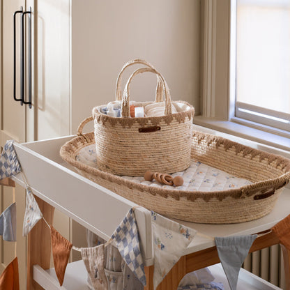 Wicker crib and basket on a white dresser with a window in the background