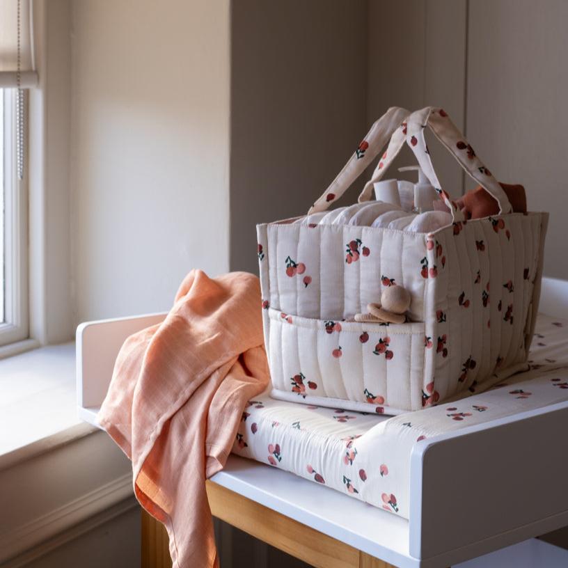 Patterned diaper bag on a bench with a pink blanket next to it