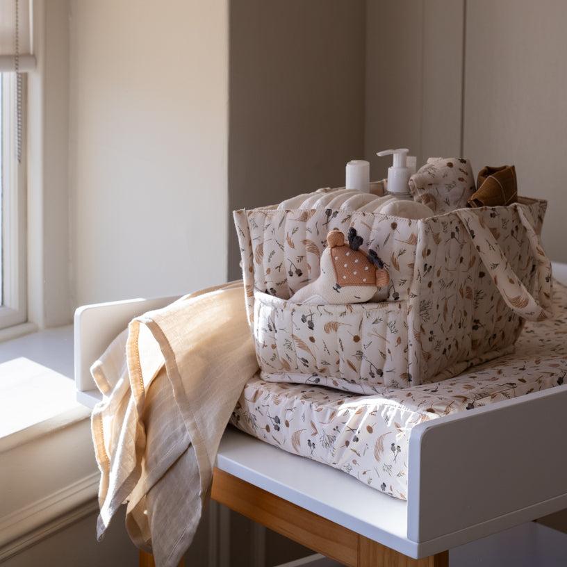 Nursery setup with baby bedding, plush toys, and bottles on a changing table.