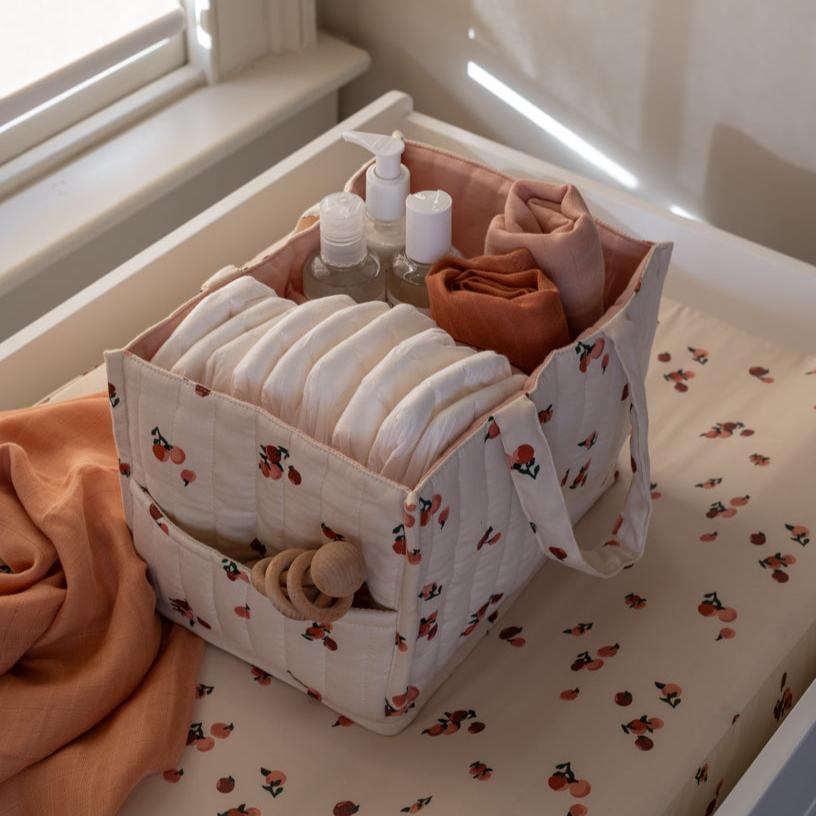 Storage basket with baby items on a crib with a floral pattern
