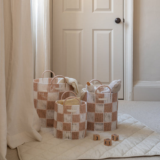 Three woven baskets on a light-colored rug with a neutral background