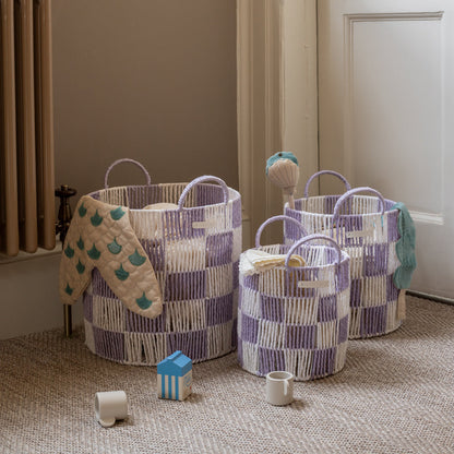 Three woven baskets with handles on a carpeted floor, surrounded by toys.