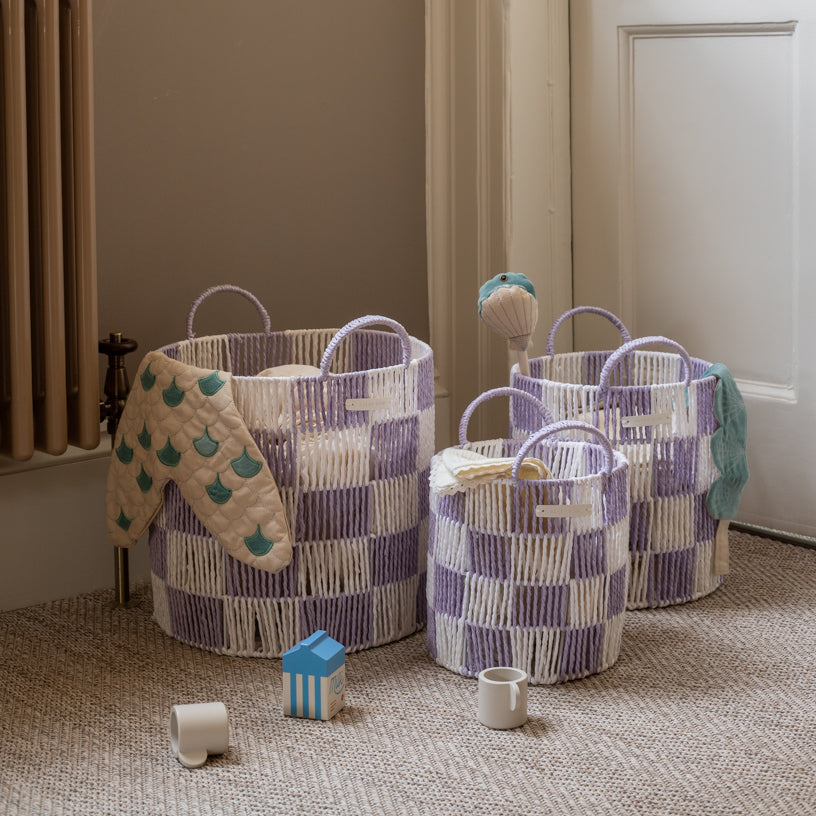Three woven baskets with handles on a carpeted floor, surrounded by children's toys.