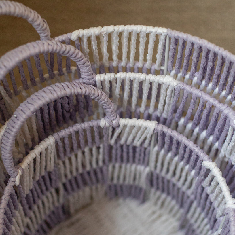 Close-up of three woven baskets with a gradient from purple to white.