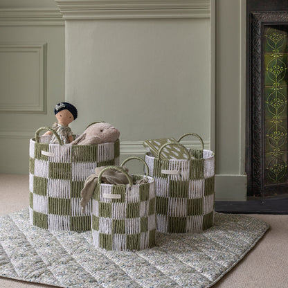 Set of three woven baskets with checkered pattern on a rug.