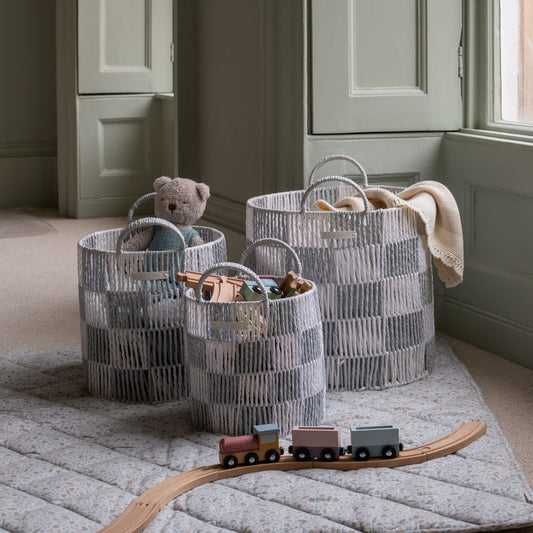 Three woven baskets with toys on a carpeted floor in a room.