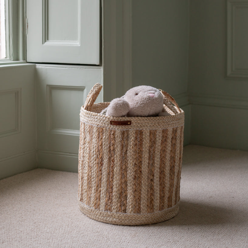 Woven basket with a plush toy inside on a carpeted floor.