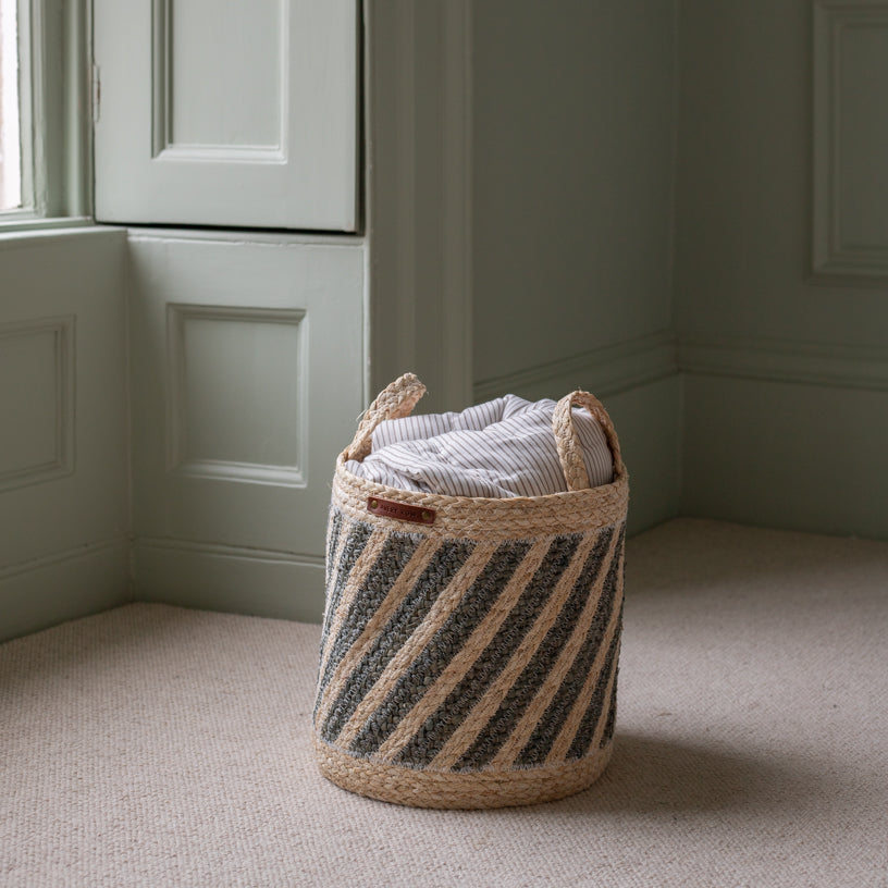 Woven laundry basket with striped pattern on a beige carpeted floor.