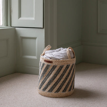 Woven laundry basket with striped pattern on a beige carpeted floor.