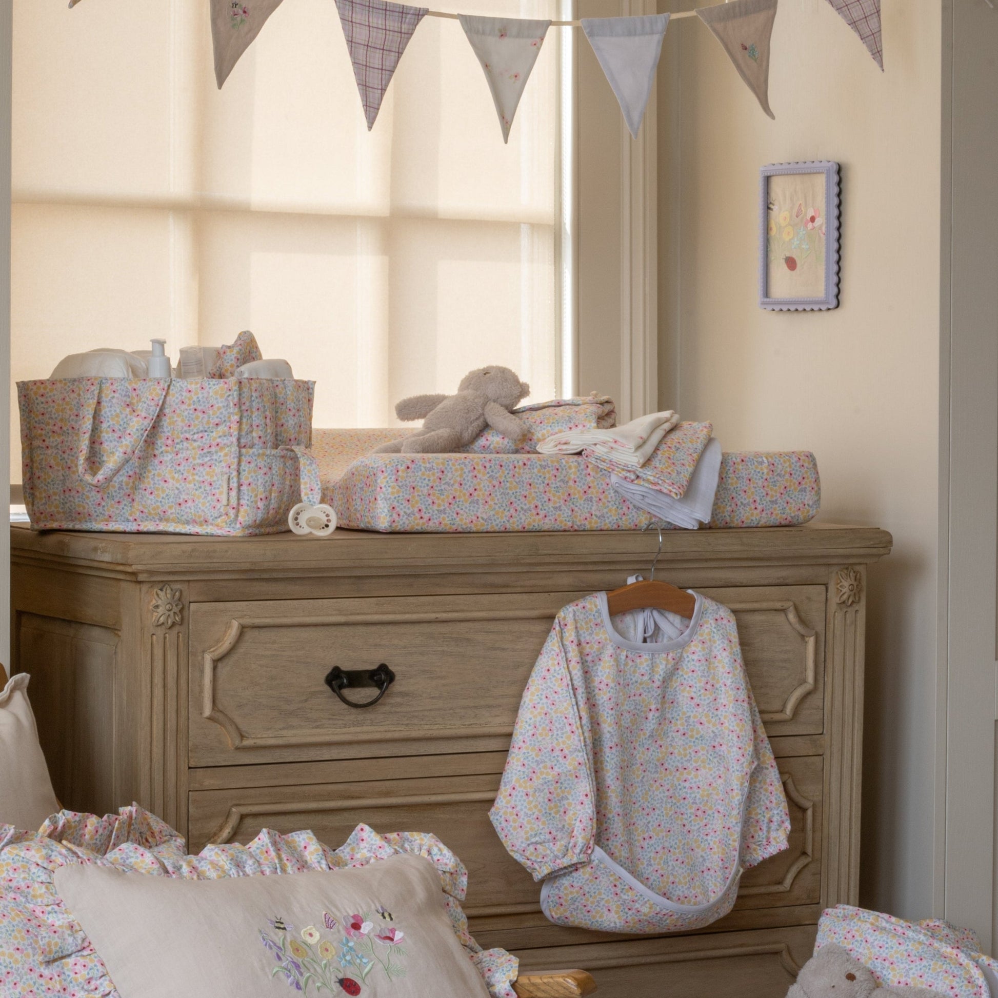 Nursery room with wooden dresser, baby clothes, and toys.