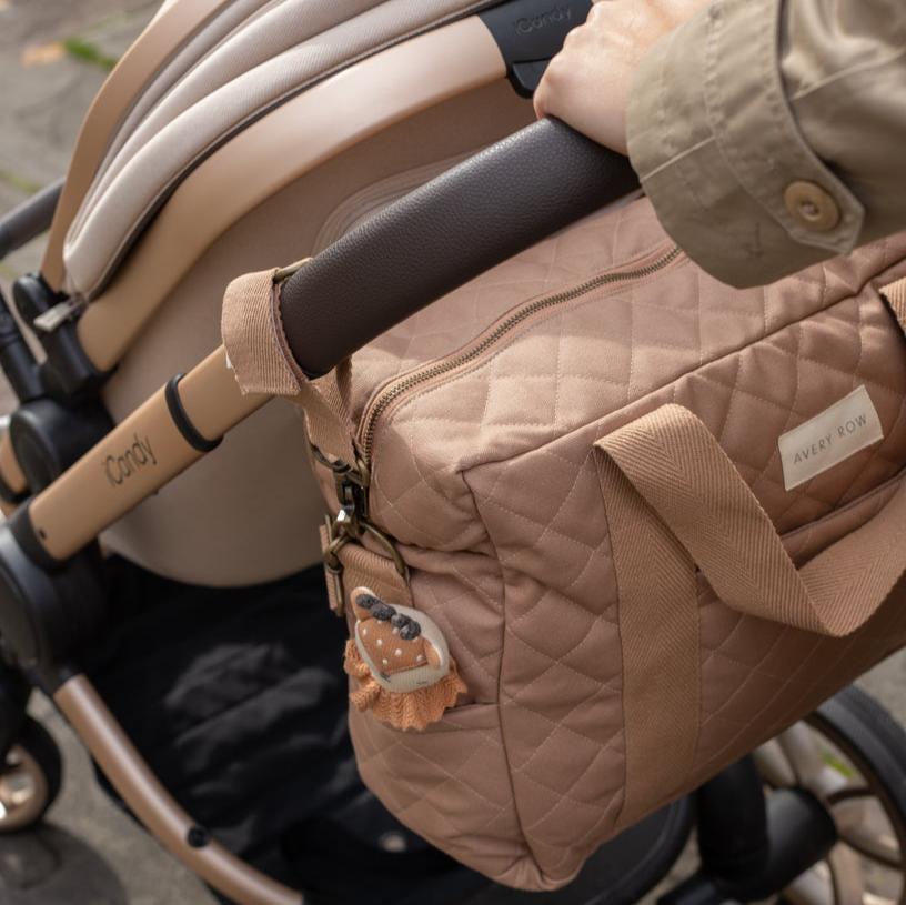 Beige quilted bag with a bear patch attached to a stroller handle.