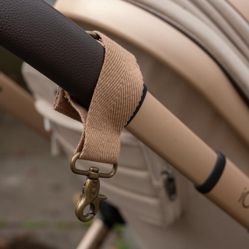 Close-up of a beige strap with a metal hook attached to a vehicle's steering wheel.