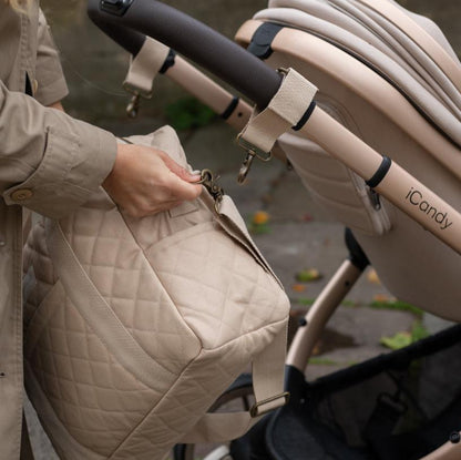 Person adjusting a beige quilted bag attached to an iCandy stroller.