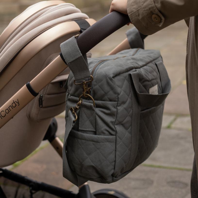 Gray quilted handbag attached to a beige stroller handle.