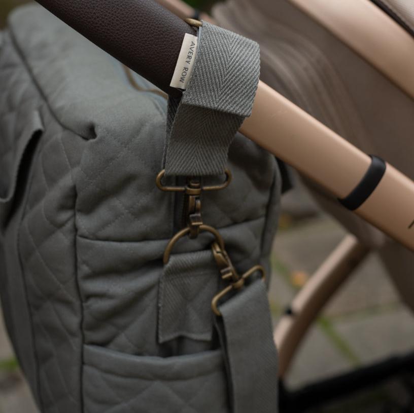 Gray quilted bag with a strap and beige handle in an outdoor setting