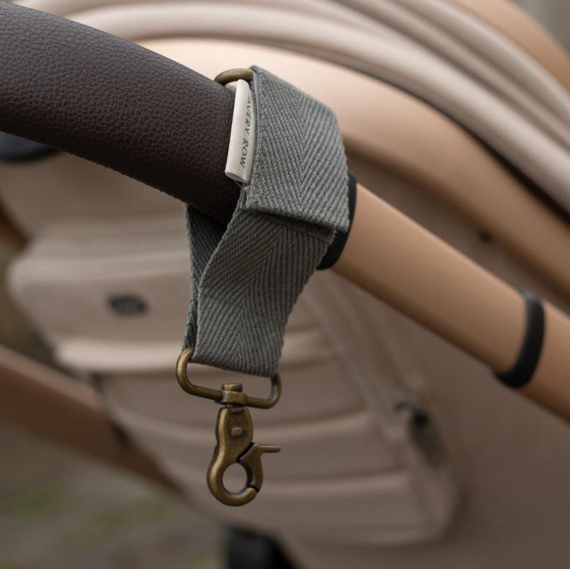Gray strap with a gold clasp attached to a vehicle's steering wheel.