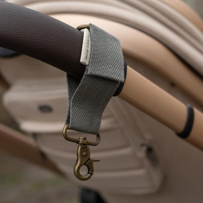 Gray strap with a gold clasp attached to a vehicle's steering wheel.