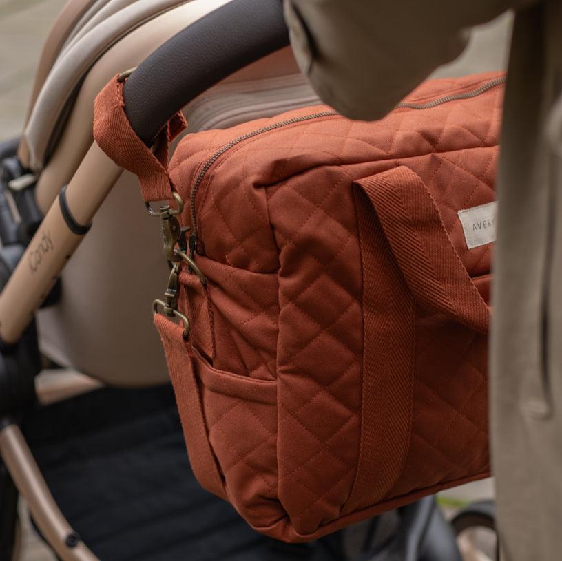 Brown quilted diaper bag attached to a stroller