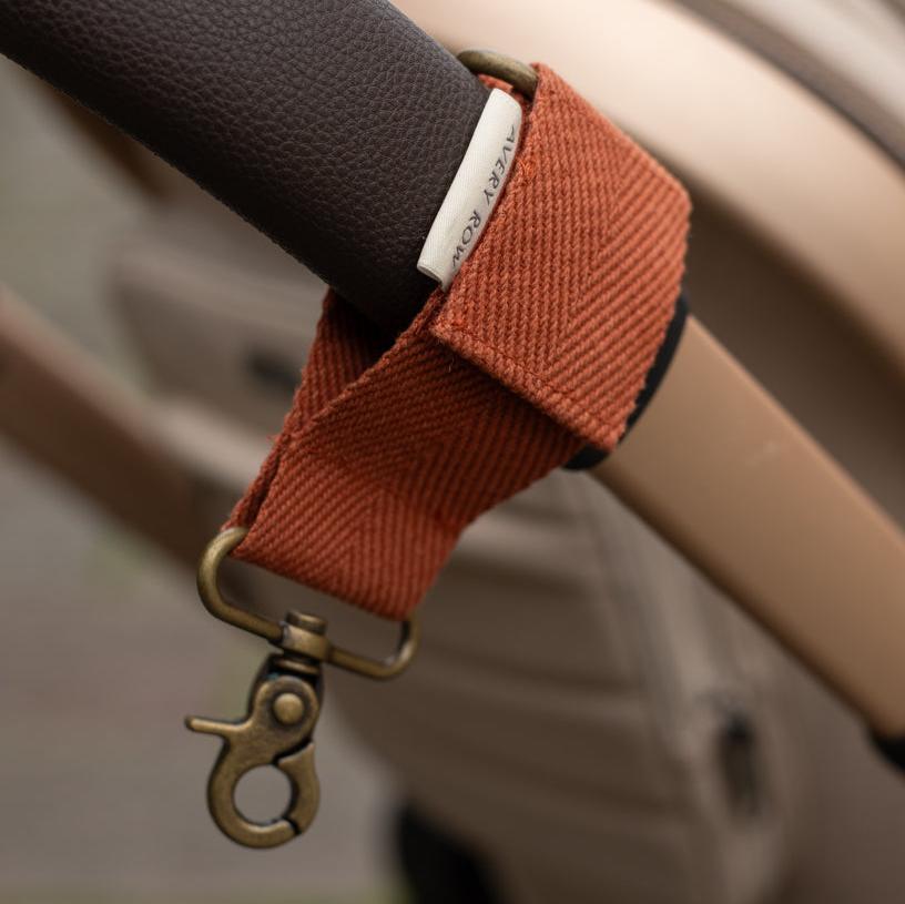 Close-up of a brown strap with a metal clasp attached to a suitcase handle.
